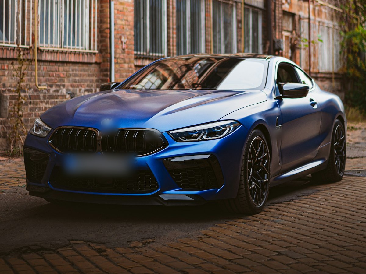 Blue performance coupe parked by a brick warehouse